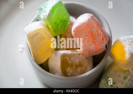 Colorful turquish delight confections, macro, white background. Cubes of variety of lokum sweets, dusted with sugar, closeup. Stock Photo