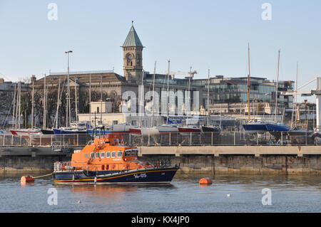 RNLI Lifeboat moored in Harbour in Dun Laoghaire in County Dublin Ireland with Dun Laoghaire Town Hall behind Stock Photo