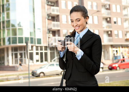 smiling businesswoman using  smart phone, outdoor Stock Photo