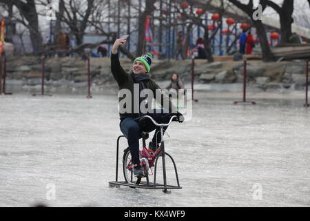 Beijing, China. 7th Jan, 2018. A tourist rides an ice bike in the ice rink at the Summer Palace in Beijing, capital of China, Jan. 7, 2018. During the weekend, many people came to the ice rink on Kunming Lake to relax or take exercise. Credit: Liu Xianguo/Xinhua/Alamy Live News Stock Photo