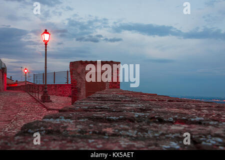 External wooden door in an old guard post of a surrounding wall with red street lights Stock Photo