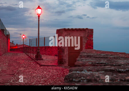 External wooden door in an old guard post of a surrounding wall with red street lights Stock Photo