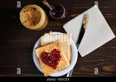 Peanut butter and heart shaped jelly sandwich on wooden background Stock Photo