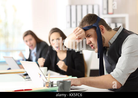 Humorous motivated businessman reaching goals with colleagues encouraging him at office Stock Photo