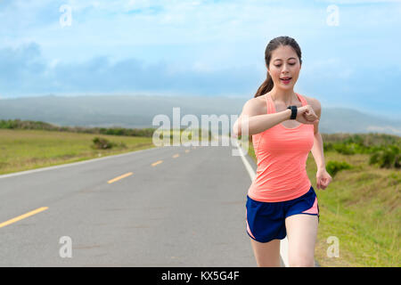 happy attractive girl runner using smartwatch system recording personal heart rate and confirm training route through GPS when she running on road wor Stock Photo
