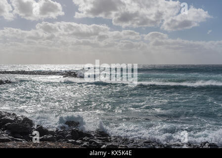 Ein sehr stürmischer Tag in Costa Teguise auf Lanzarote lässt Wellen am Strand brechen. Der Himmel ist wolkenverhangen und der Regen wird prasseln. Stock Photo