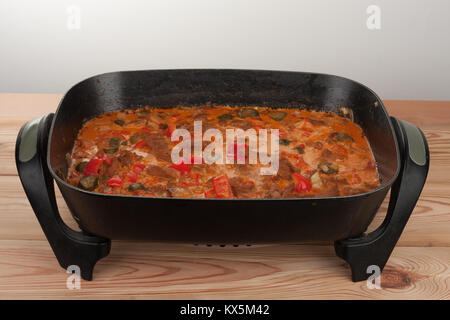 Soy noodles  with tomatoe sauce, paprika, cucumber and milk cream on baking pan on wooden table. Stock Photo