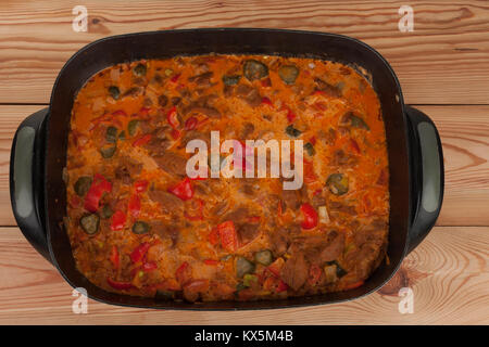 Soy noodles  with tomatoe sauce, paprika, cucumber and milk cream on baking pan on wooden table. Stock Photo