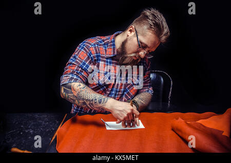 Tanner performing leatherwork on a new product piece in the workshop Stock Photo
