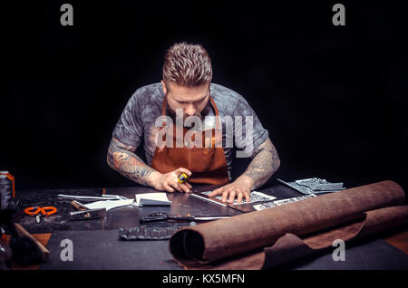 Man working with leather cutting out leather goods in his leather shop Stock Photo