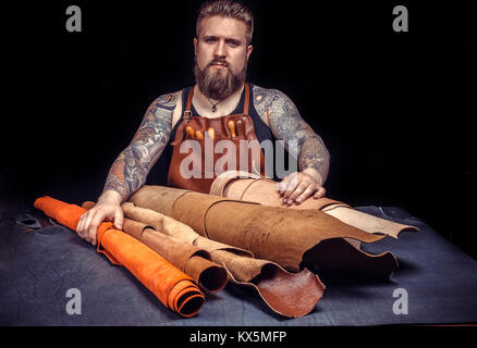 Handyman cuts out leather goods at the tanner shop Stock Photo