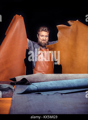 Leather Artist processes a workpiece from leather in studio Stock Photo