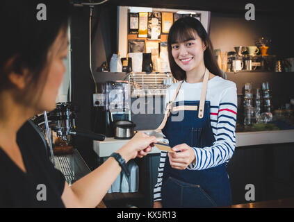 customer pay coffee drink with credit card to barista at counter bar in cafe,Food and drink business,billing payment Stock Photo