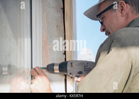 Carpenter in glasses with a drill Stock Photo