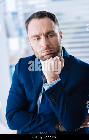 Confident smart businessman sitting with his chin resting on his fist Stock Photo