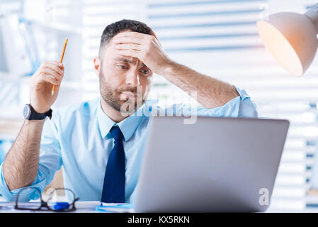 Worried young specialist feeling upset while noticing a mistake in his work Stock Photo