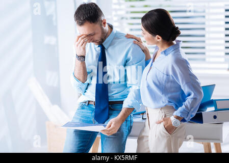 Tired man touching his forehead while a kind woman comforting him Stock Photo