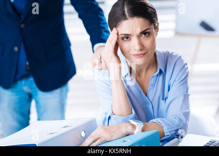 Worried woman touching her forehead while having a headache at work Stock Photo