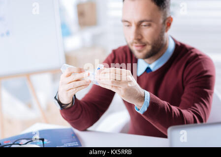 Attentive man looking at the pillbox before taking a pill from it Stock Photo