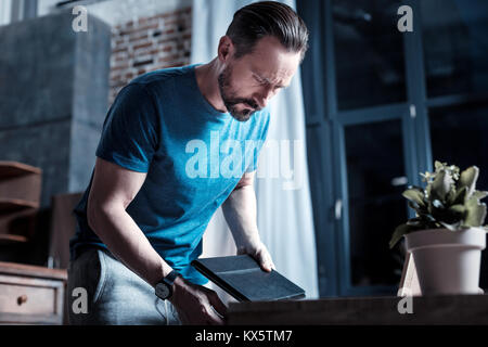 Serious man putting tablet in the table Stock Photo