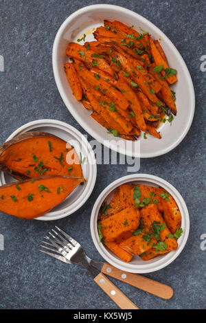 Different types of baked sweet potato with curry and a creamy garlic sauce. Healthy vegan food concept. Stock Photo
