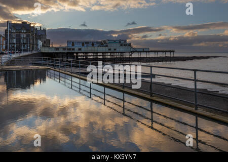 Aberystwyth's promenade paddling pool mirroring the sky in winter with the pier in the background Stock Photo