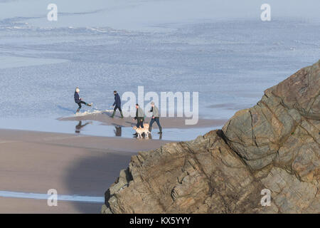 A family walking their dogs at low tide along Great Western Beach Newquay Cornwall. Stock Photo