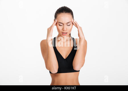 Portrait of a young asian fitness woman suffering from headache isolated over white background Stock Photo