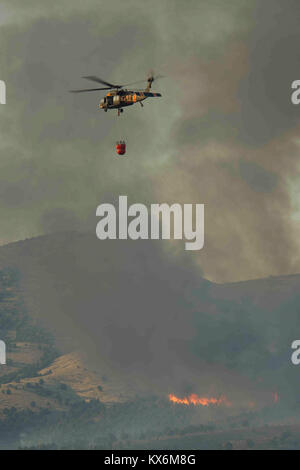 Utah National Guard Detachment 2, Company C, 1st General Support Aviation Battalion, 171st Aviation Regiment from West Jordan, Utah, performs water drops with a 'Bambi Bucket' onto a wildfire on Utah Training Center Camp Williams, Utah, 6 Aug. 2012.  Bambi Buckets are a trade marked name for collapsible water buckets made by SEI Industries, a Canadian company. They can dump 660 of gallons of water on a fire at a time.  (U.S. Air Force photo by Tech. Sgt. Dennis J. Henry Jr./Released) Stock Photo