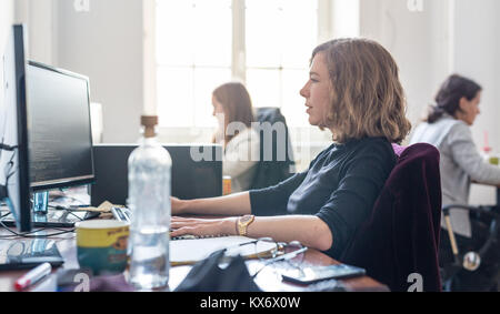 Yound devoted female software developers team working on desktop computer in IT statup company. Stock Photo