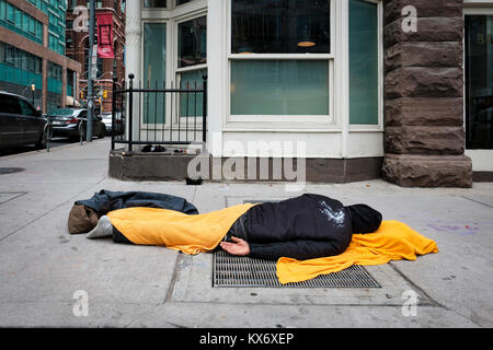 Homeless man sleeping on the sidewalk covered with blanket in downtown Toronto, Ontario, Canada. Stock Photo