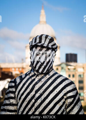 London, UK. 7th Jan, 2018. A striped painted street performer stands motionless in the afternoon light framed by St. Paul’s Cathedral. Credit: Guy Corbishley/Alamy Live News Stock Photo