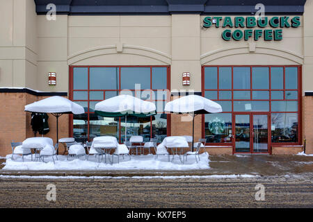 Empty Starbucks Coffee sidewalk patio tables, chairs, and umbrellas covered by fresh snow, winter scene, London, Ontario, Canada Stock Photo