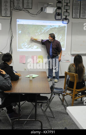 Galena, AK - Paul Apfelbeck, English and journalism teacher at the Galena Interior Learning Academy, shows students an aerial image of the spring flooding along the Yukon River that displaced residents and caused school to open later than usual on Sept. 9.   GILA, which sits in an area once occupied by an Air Force base, was saved from major flood damage by a dike that was built to protect the airfield from annual flooding.   In late May, huge sheets of ice clogged the Yukon downstream from Galena. The river's water rapidly rose and breached its banks, flooding the town, destroying homes, and  Stock Photo