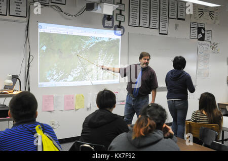 Galena, AK - Paul Apfelbeck, English and journalism teacher at the Galena Interior Learning Academy, shows students an aerial image of the spring flooding along the Yukon River that displaced residents and caused school to open later than usual on Sept. 9.   GILA, which sits in an area once occupied by an Air Force base, was saved from major flood damage by a dike that was built to protect the airfield from annual flooding.   In late May, huge sheets of ice clogged the Yukon downstream from Galena. The river's water rapidly rose and breached its banks, flooding the town, destroying homes, and  Stock Photo