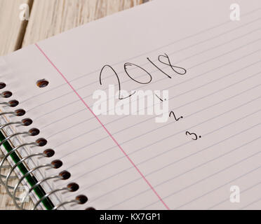 2018 to do list written on a white notebook in black ink with the notebook laying on a white wooden table Stock Photo