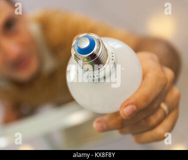 A closeup of hands putting in and twists a bulb standing on a ladder Stock Photo