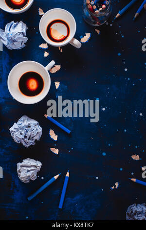 Dark background with crumpled paper balls, empty coffee cups, pencils, paper, notes and notepads. Still life with writer workplace. Creative writing concept. Stock Photo