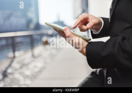 Man is holding a Tablet PC outdoors and typing on the touch screen Stock Photo
