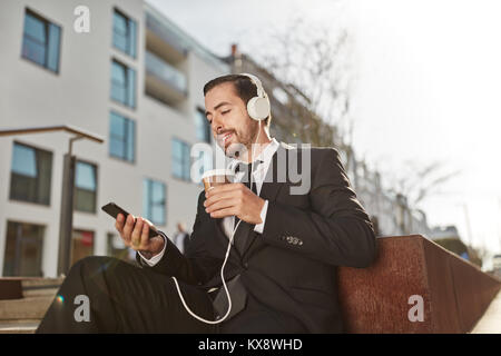 Smiling business man uses smartphone app in a coffee break Stock Photo