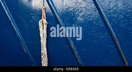 A up close photo of a used boat rope and a blue painted metal rough surface texture Stock Photo