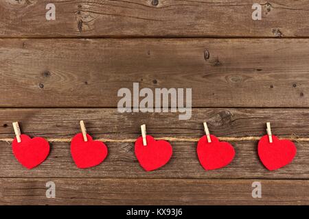 Cloth hearts hanging from line, bottom border against a rustic old wood background Stock Photo