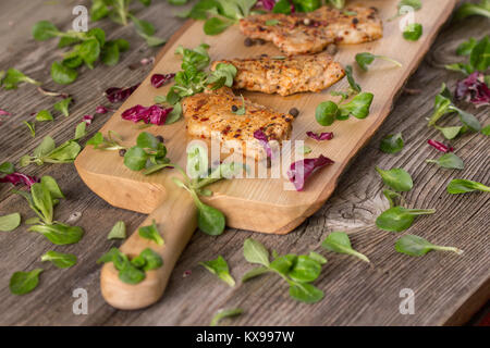 Fresh freshly fried delicious slices of meat on a wooden board with fresh herbs. Appetizing steaks on a wooden board. Stock Photo