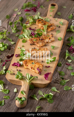 Fresh freshly fried delicious slices of meat on a wooden board with fresh herbs. Appetizing steaks on a wooden board. Stock Photo