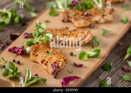 Fresh freshly fried delicious slices of meat on a wooden board with fresh herbs. Appetizing steaks on a wooden board. Stock Photo