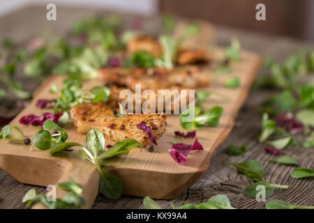 Fresh freshly fried delicious slices of meat on a wooden board with fresh herbs. Appetizing steaks on a wooden board. Stock Photo