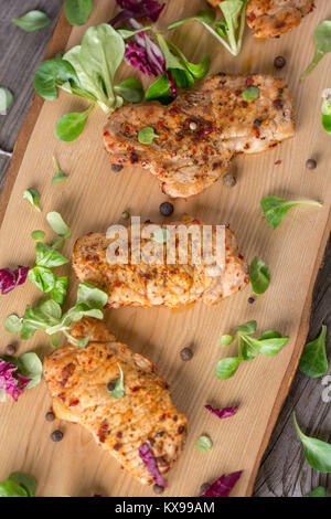 Fresh freshly fried delicious slices of meat on a wooden board with fresh herbs. Appetizing steaks on a wooden board. Stock Photo