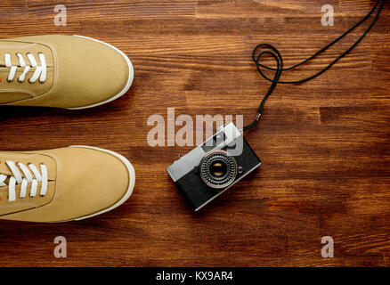 Vintage camera with sneakers on wooden background. Travel background. Horizontal Stock Photo