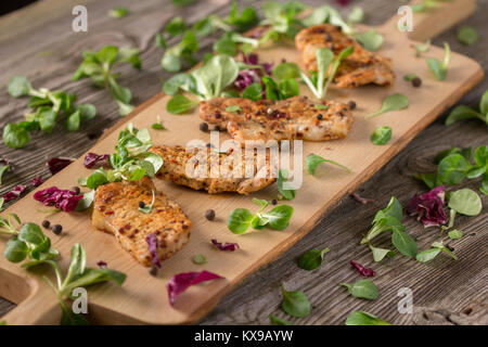 Fresh freshly fried delicious slices of meat on a wooden board with fresh herbs. Appetizing steaks on a wooden board. Stock Photo