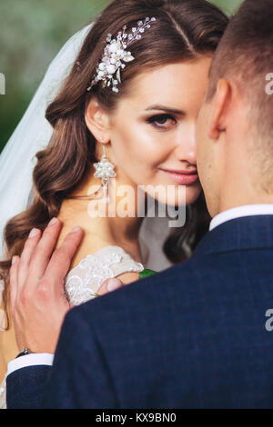 Beautiful wedding couple in park. They kiss and hug each other Stock Photo